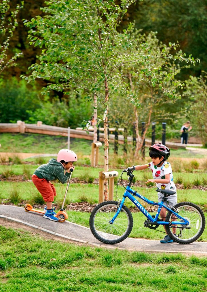 Children playing with bicycles at Oxhey Activity Park in Oxhey Village near Watford