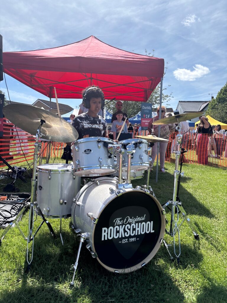 A boy from Watford Rock School playing drums at the Oxhey Village Summer Fayre 2026