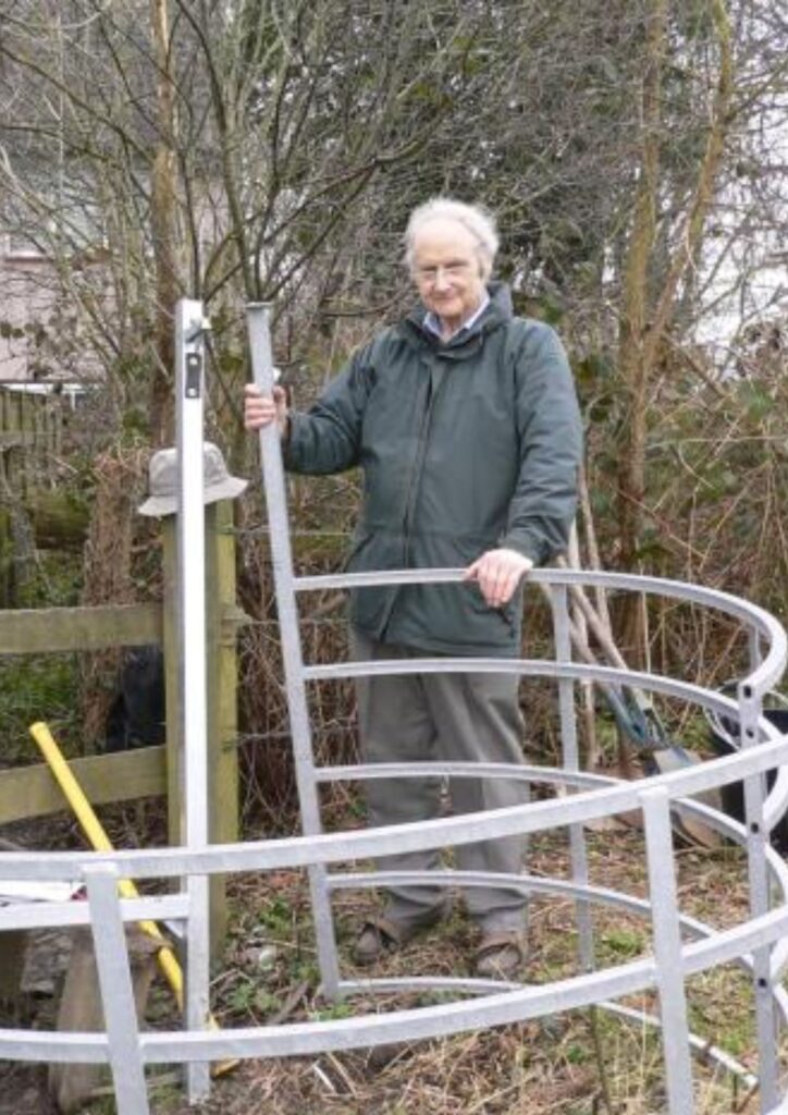 Right of Way campaigner Chris Beney standing with kissing gates on Farm Way in Bushey, Hertfordshire