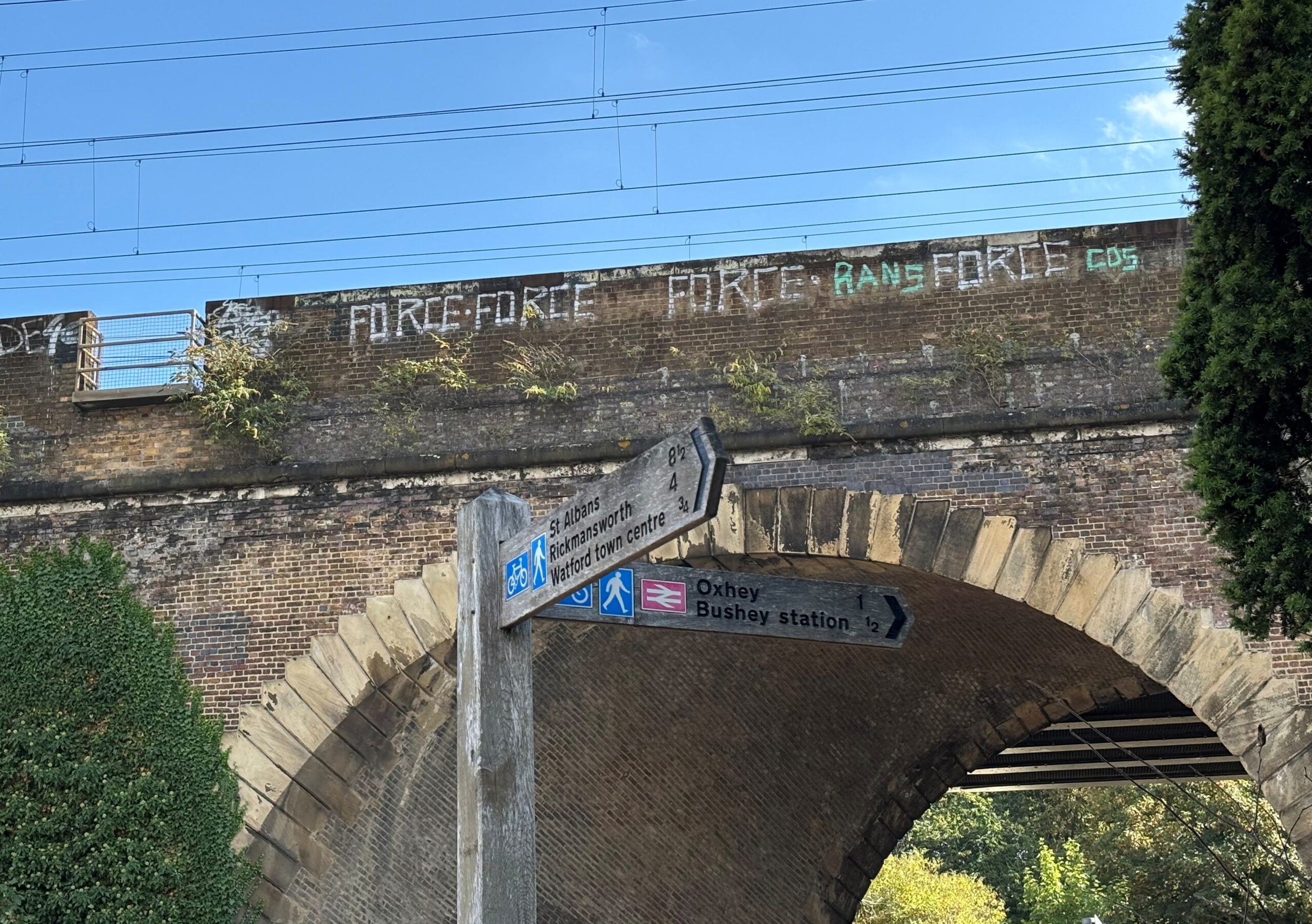 View of Bushey Arches from Lower High Street with a street sign pointing towards Oxhey, St Albans and Rickmansworth